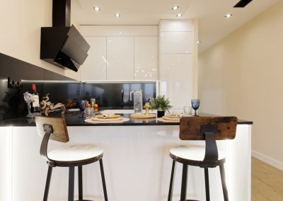 Cocina blanca con barra, dos taburetes y electrodomésticos integrados