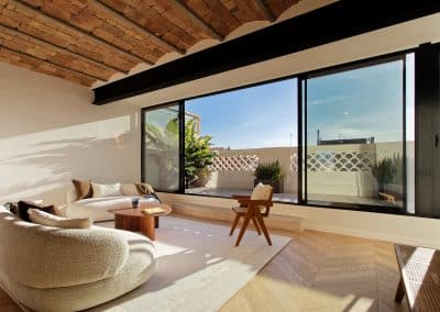 Salón con techo de bóveda catalana, mobiliario contemporáneo y ventanal panorámico