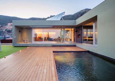 Fachada moderna con piscina y ventanales panorámicos al atardecer
